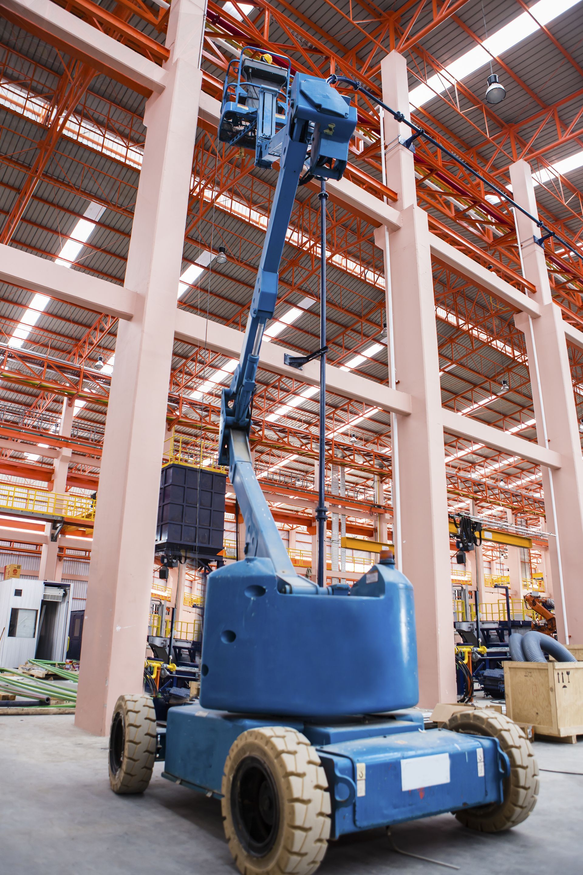 Orange and black crawler crane on a construction site with hook hanging.