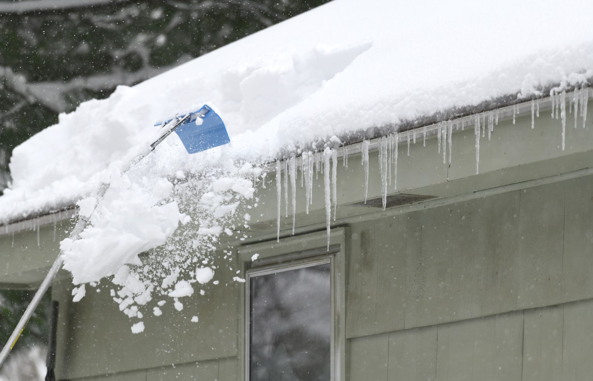 homeowner roof raking during New England snow storm.