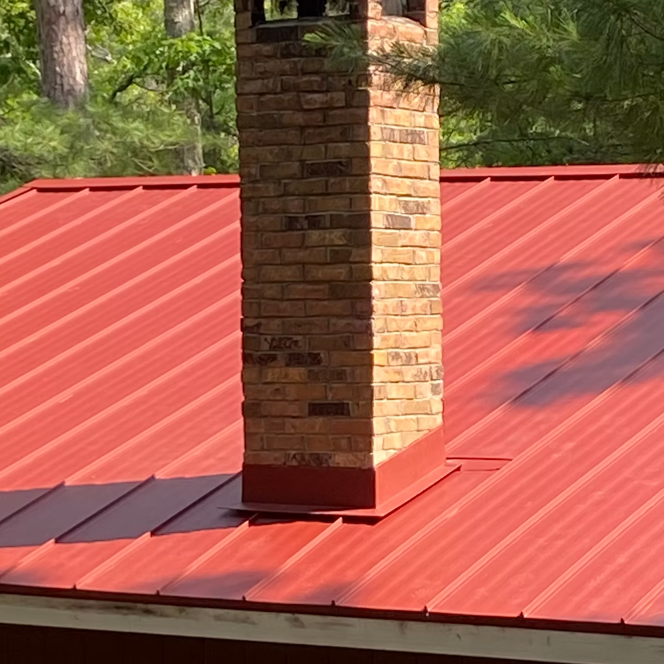 Red metal roof with brick chimney.