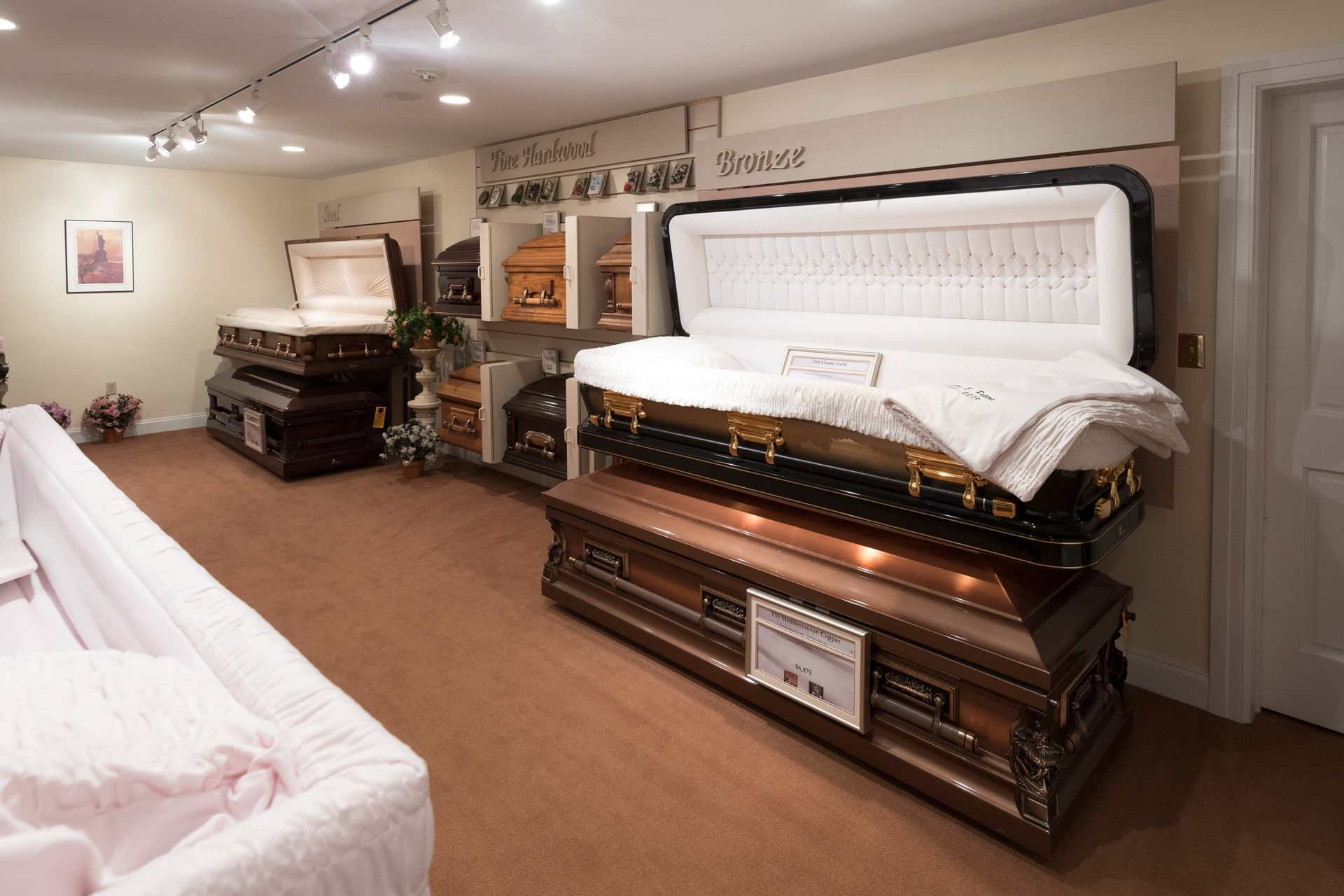 Showroom with several open white and black caskets on display in a carpeted room