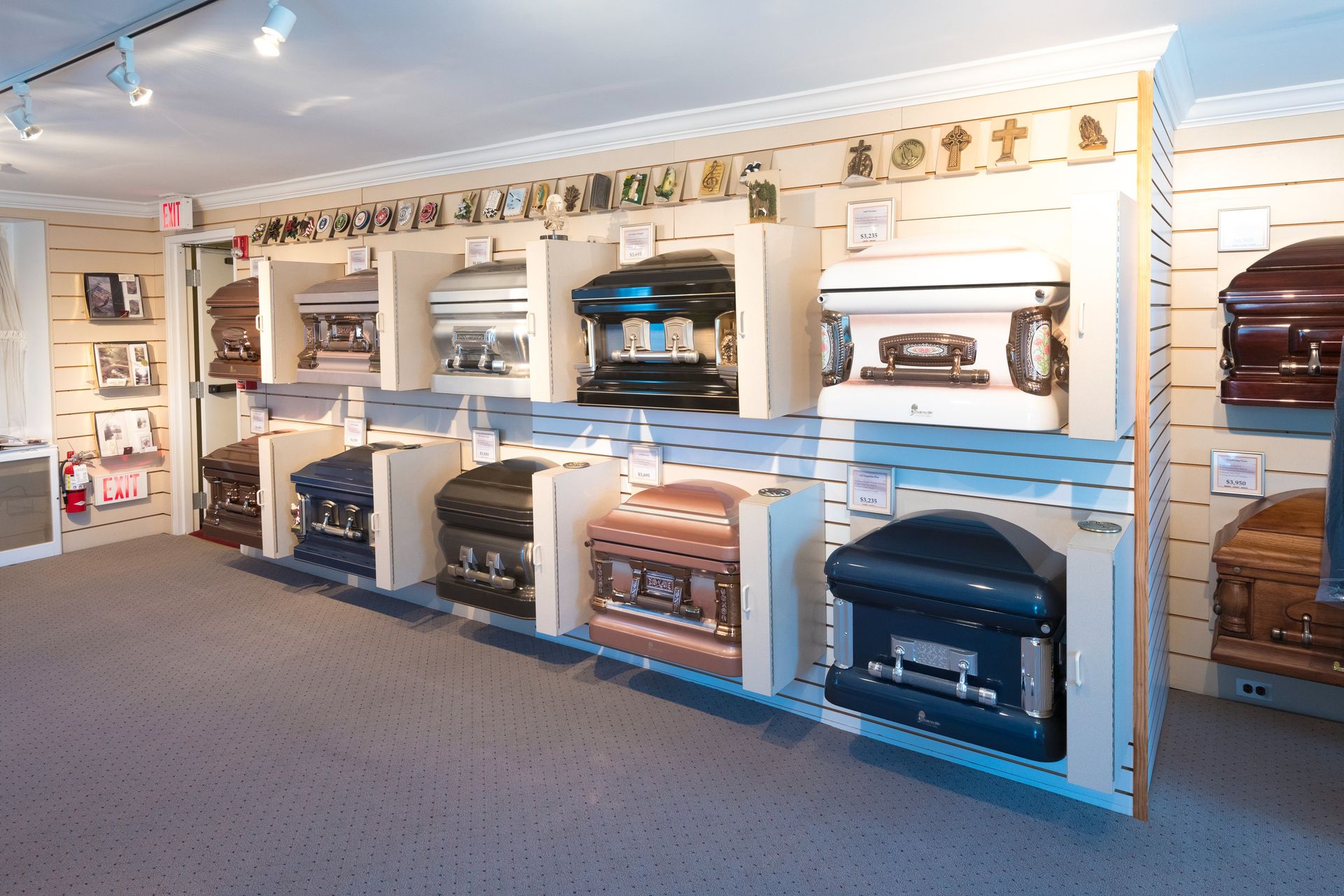 Appliance showroom with multiple colorful fireplaces and stoves displayed on white shelving units