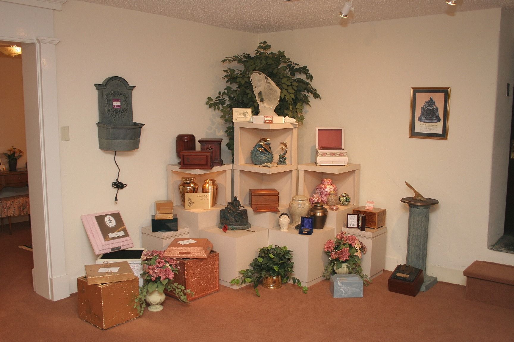 Decorated room display with shelves, plants, framed art, and small decorative items on carpeted floor
