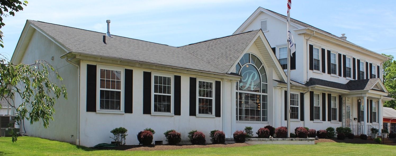 White two-story suburban house with a porch, black shutters, and a manicured lawn