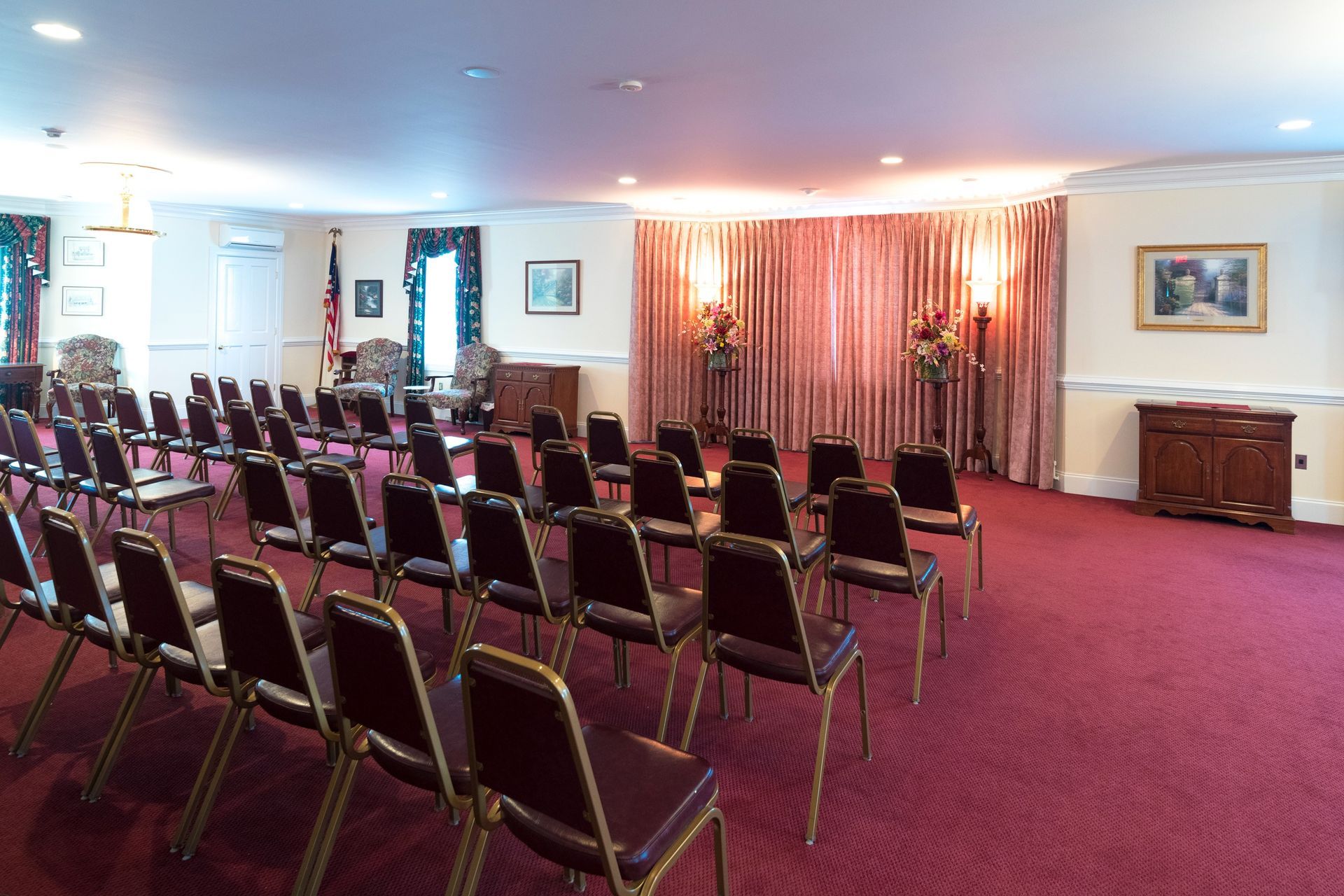 Conference room with rows of empty chairs facing a curtained presentation area