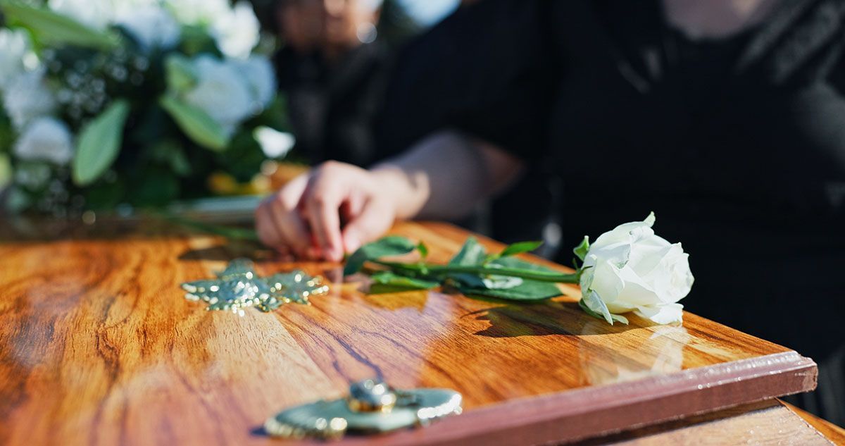Man in a gray suit reading a book beside a white floral arrangement at a formal event