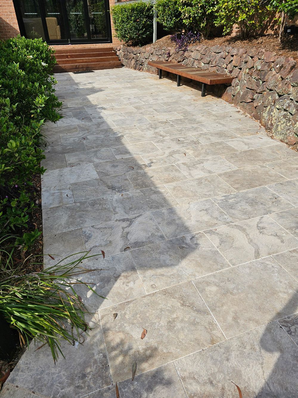 A stone walkway leading to a house with a wooden bench.