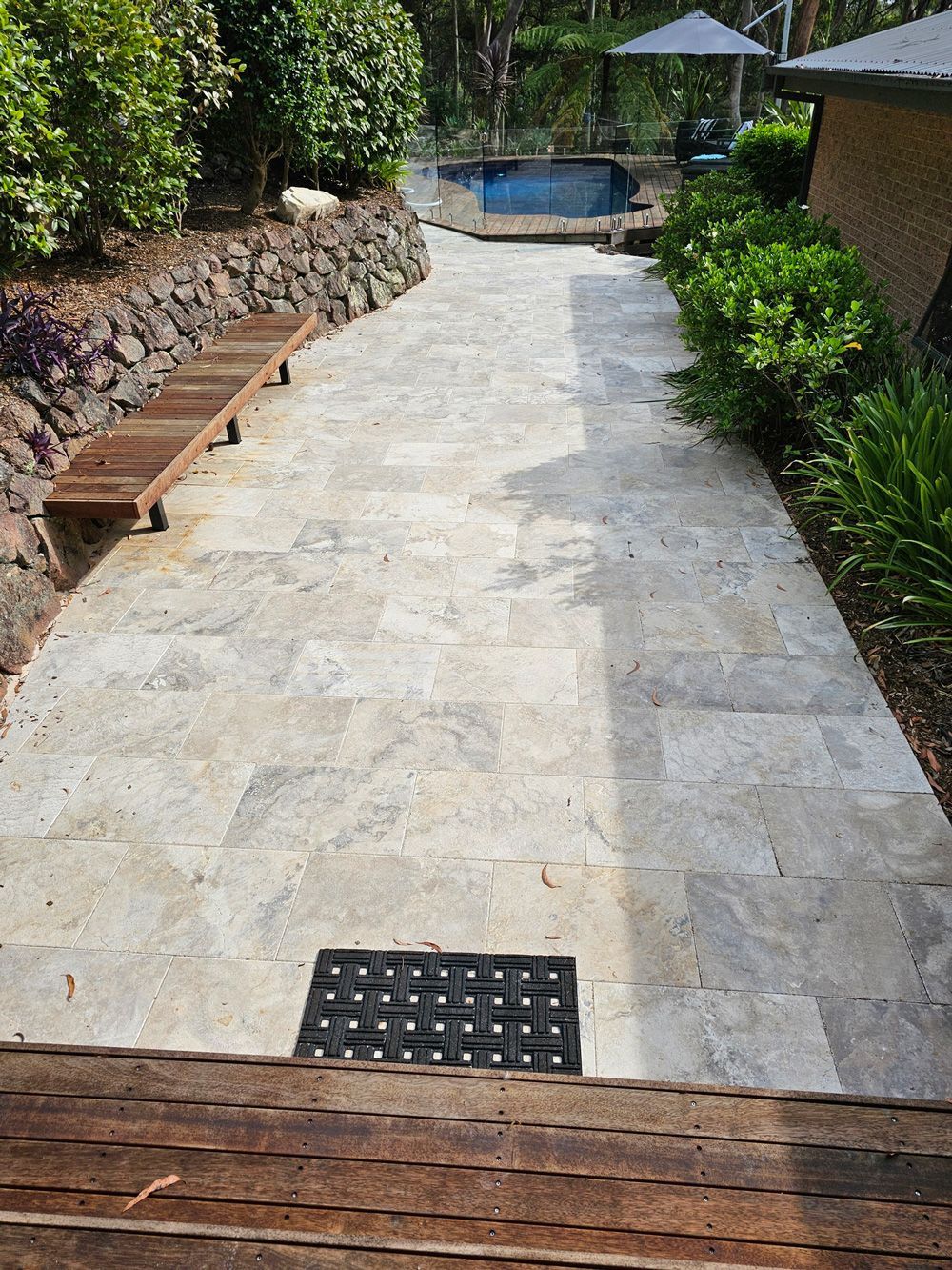 A walkway leading to a swimming pool in a backyard.