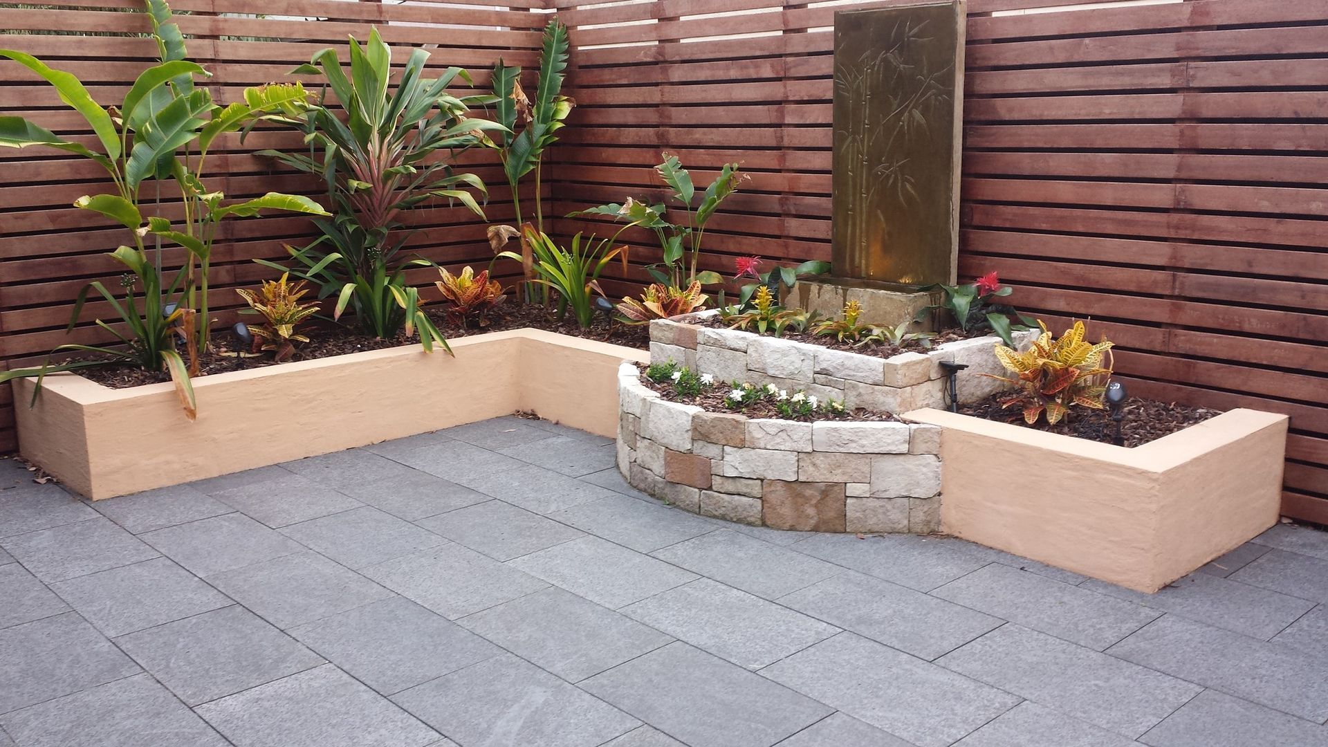 A patio with planters and a waterfall in the background