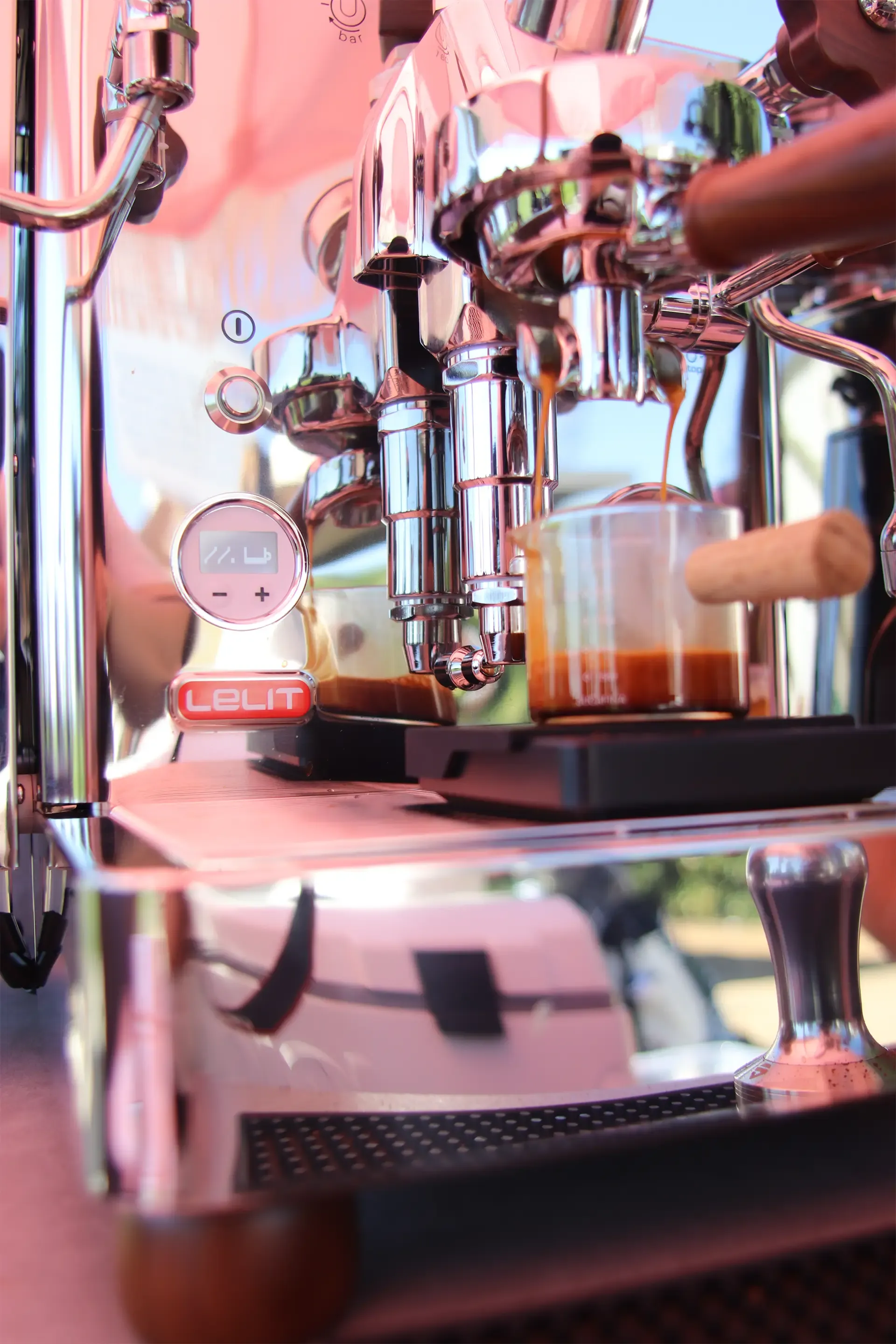 Chrome espresso machine brewing coffee in a café, with a cup and portafilter visible.