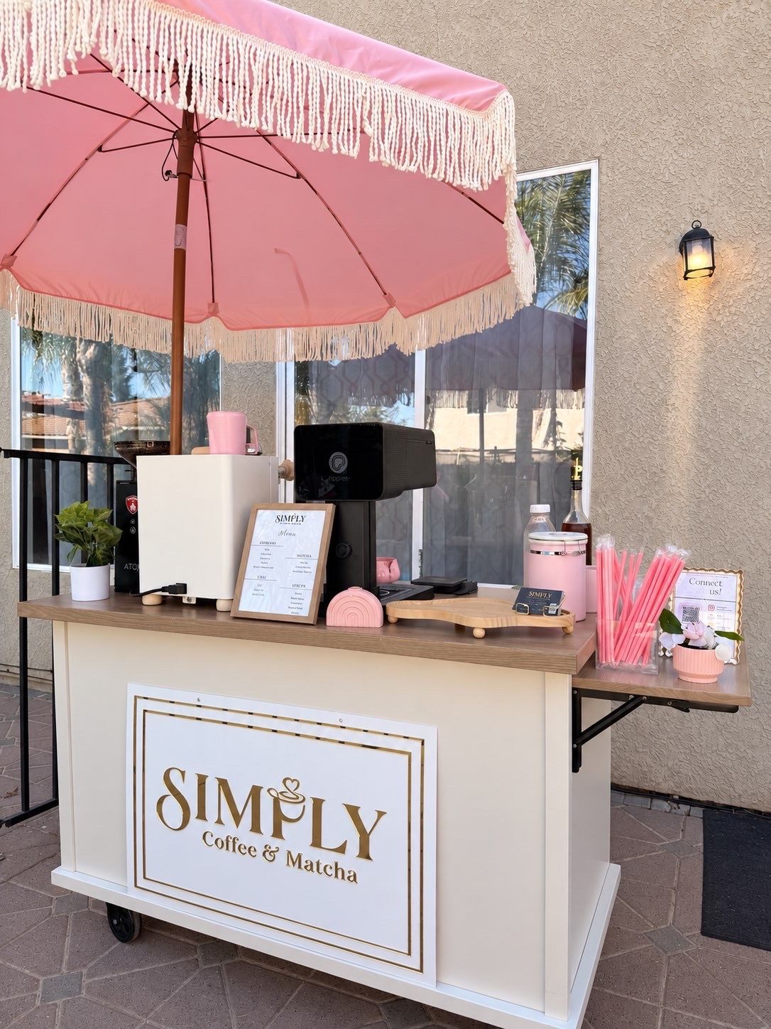 Coffee and mochi kiosk with pink umbrella and fringe canopy at an outdoor market booth