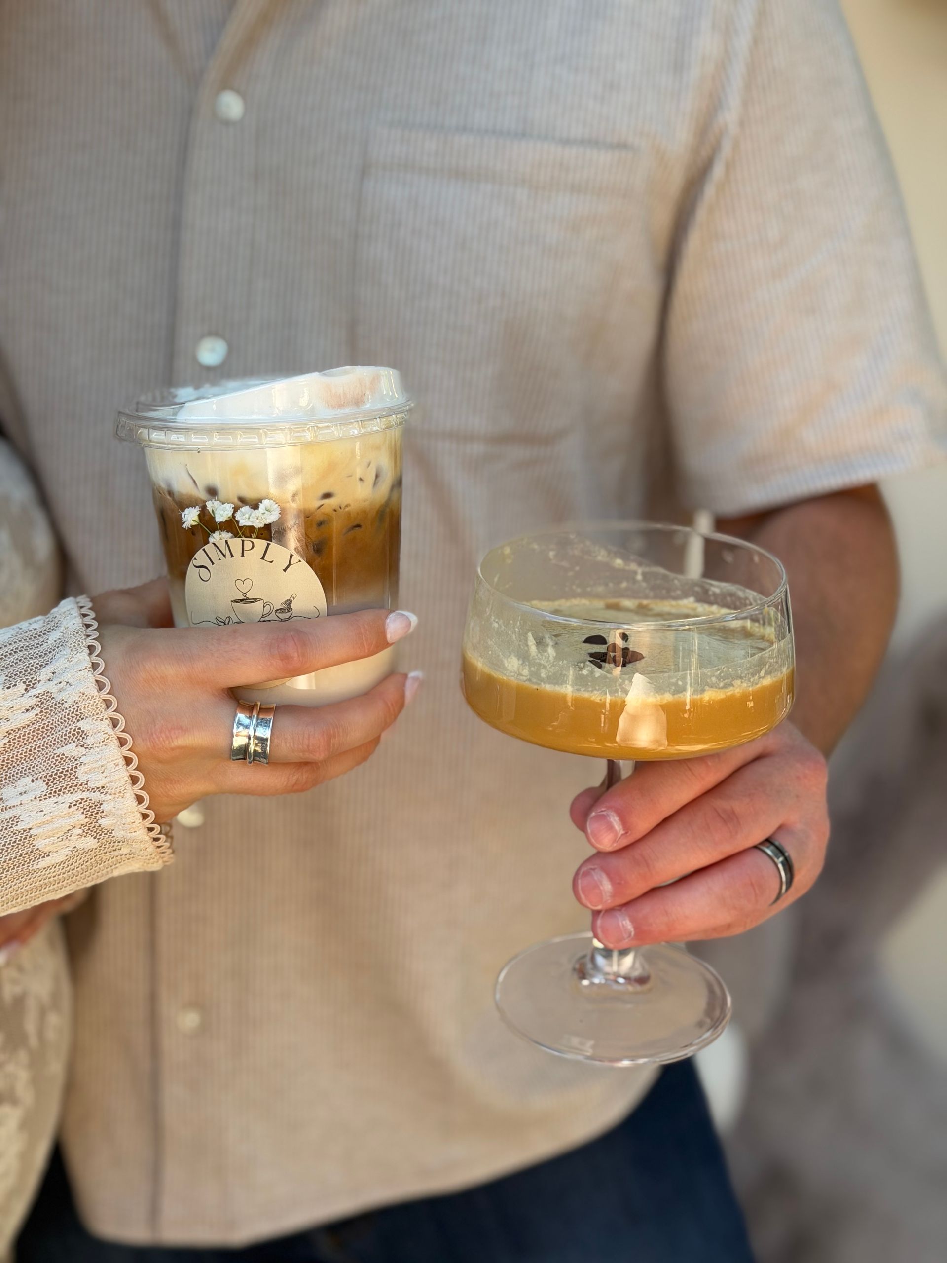 Two people holding frothy cocktails in a cozy indoor setting
