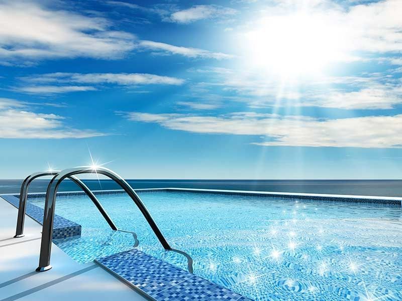 A Swimming Pool With Stairs Leading And The Sun Shining Through The Clouds — Aquatic Pool & Spa Services In Yeppoon, QLD