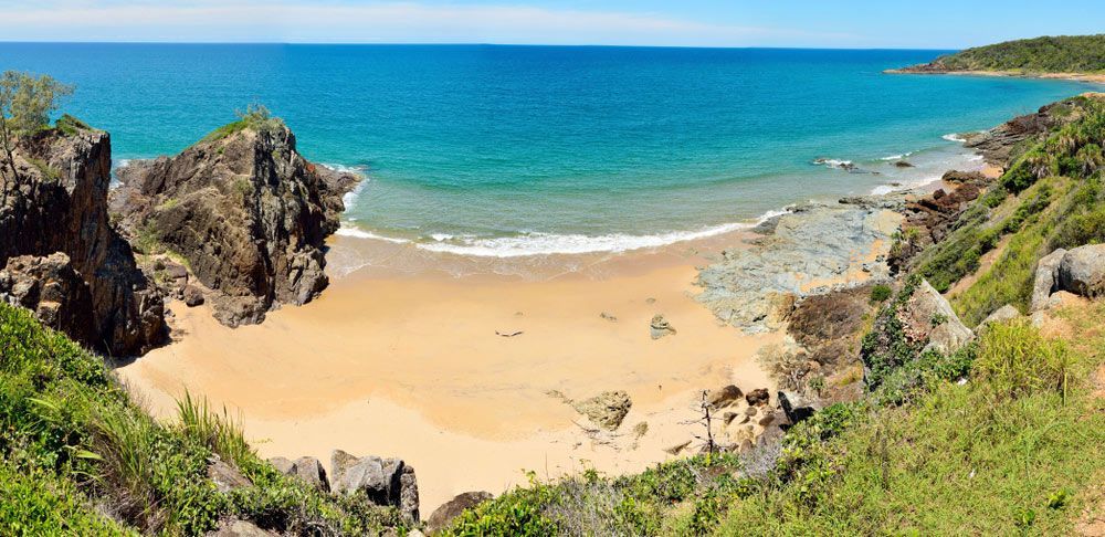 A View Of A Beach From A Cliff Overlooking The Ocean — Aquatic Pool & Spa Services In Rockhampton, QLD