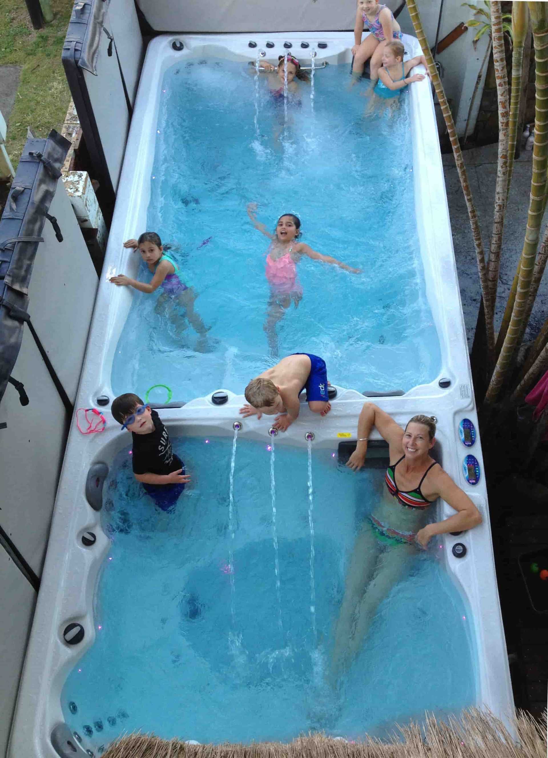 A Group Of People Are Swimming In A Large Swimming Pool — Aquatic Pool & Spa Services In Yeppoon, QLD