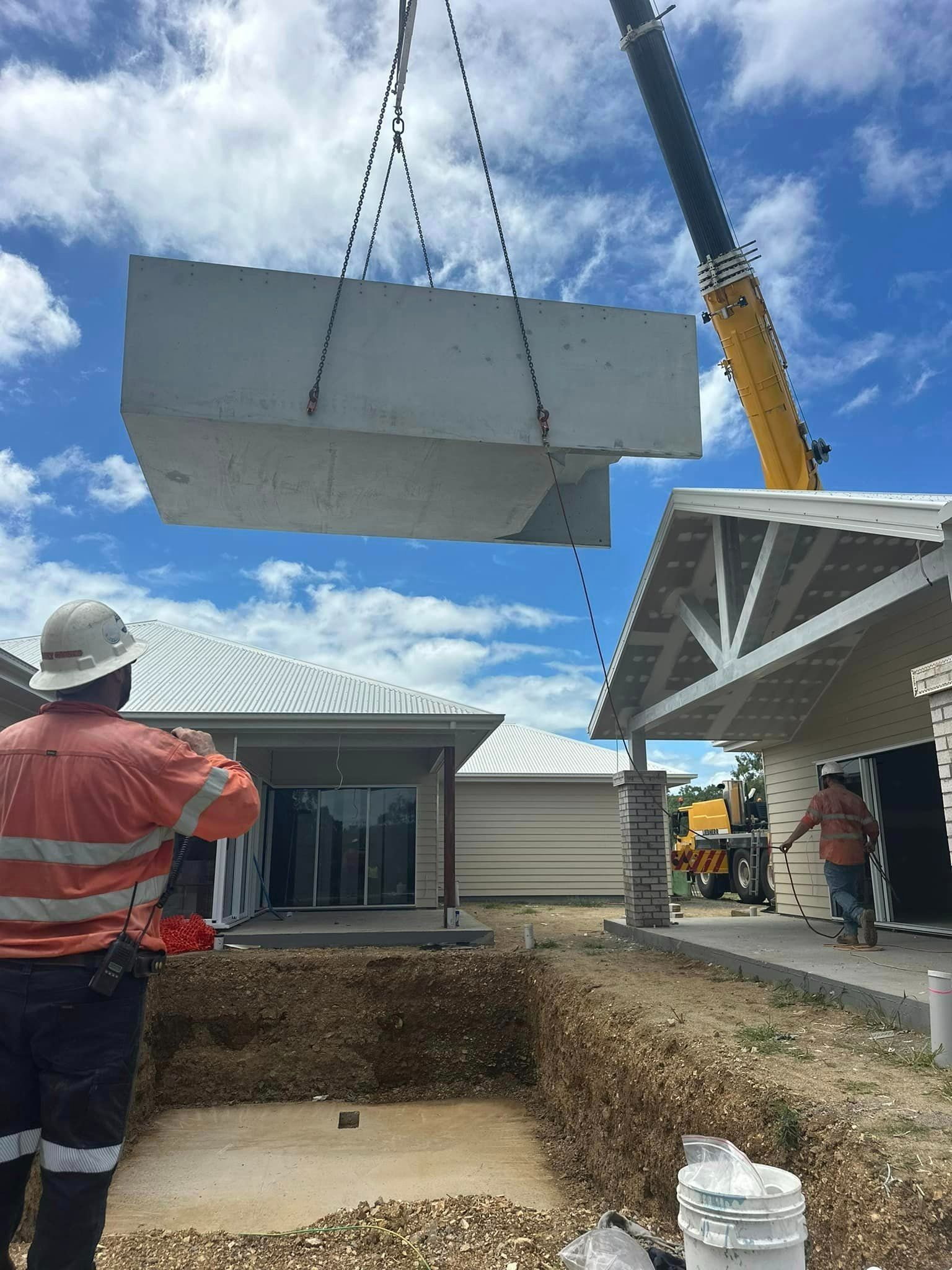 A Crane Is Lifting A Large Piece Of Concrete Into A Hole In Front Of A House  — Aquatic Pool & Spa Services In Gladstone, QLD
