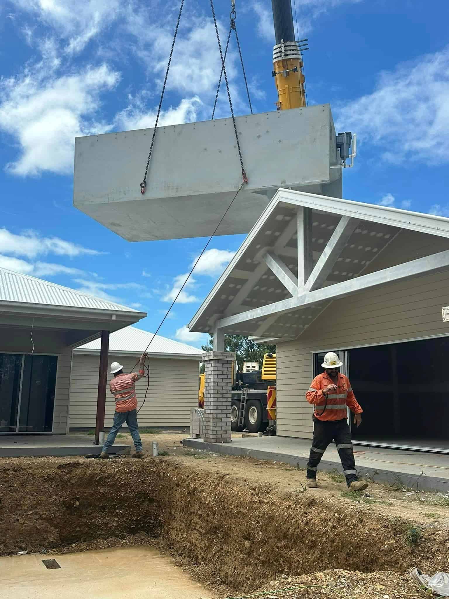 A Crane Is Lifting A Large Piece Of Concrete Into A House — Aquatic Pool & Spa Services In Yeppoon, QLD
