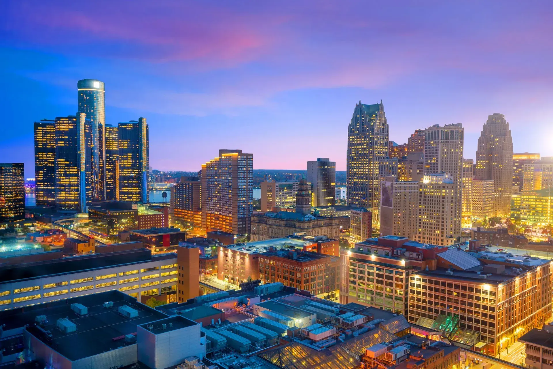 City skyline at dusk with illuminated high-rises and a pink-blue twilight sky