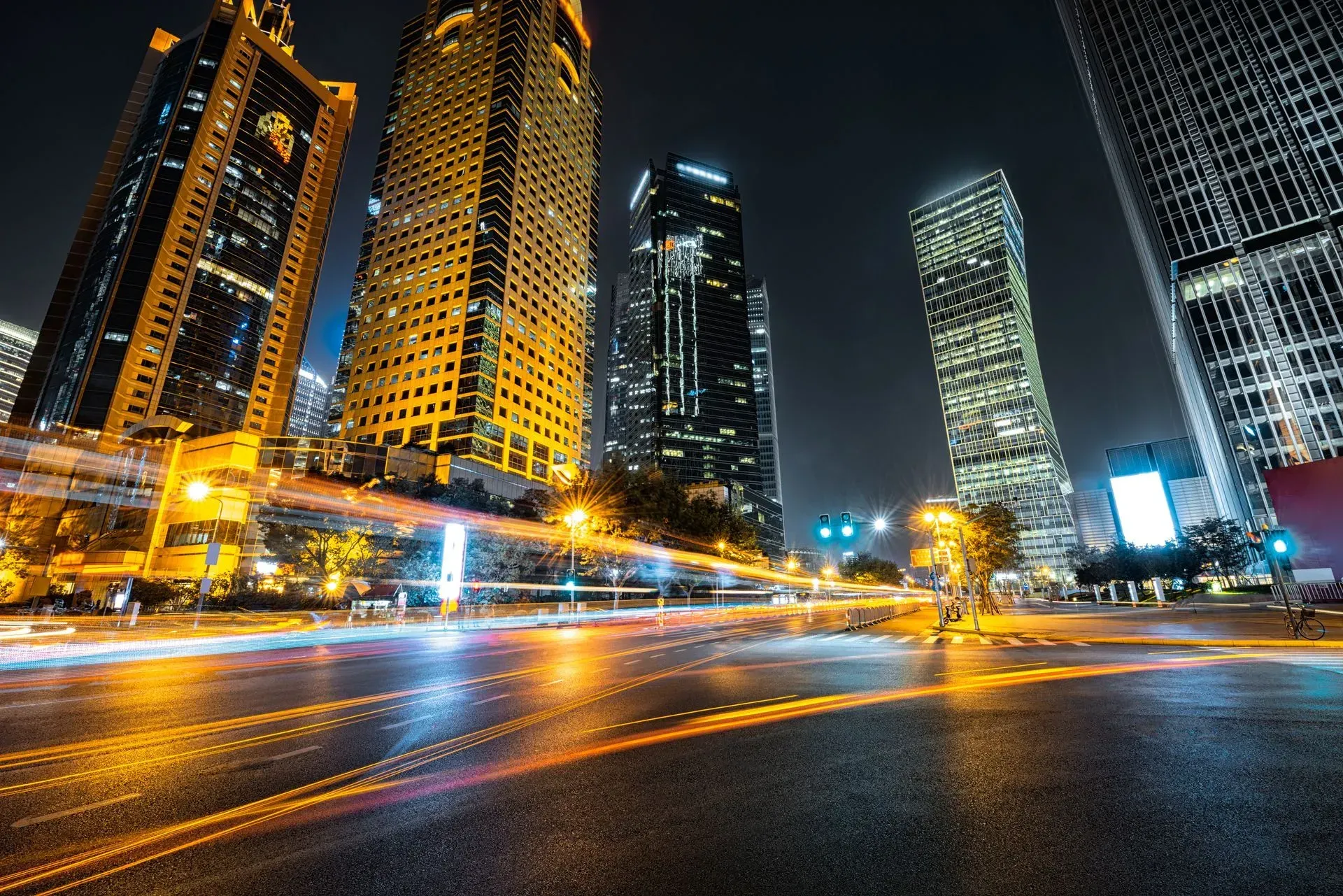 Night city skyline with illuminated skyscrapers and light trails on a wet street