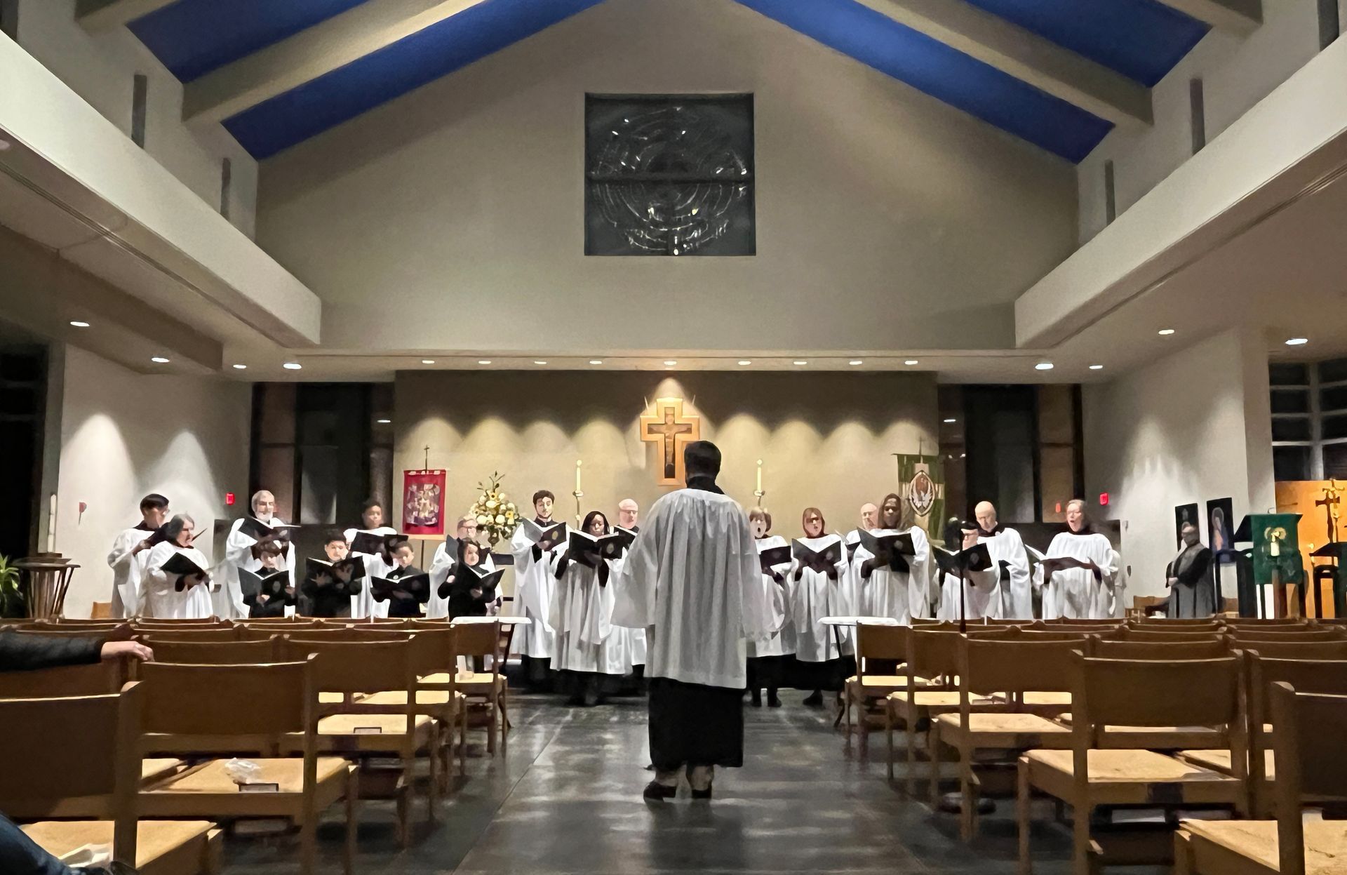 Choir performing in a church sanctuary, viewed from the aisle toward the altar.