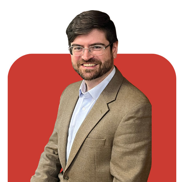 Smiling man in glasses and tan blazer against a red background