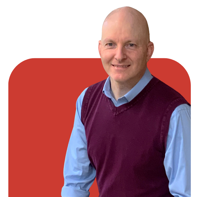 Portrait of a smiling bald man in a blue shirt and burgundy sweater vest against a red background