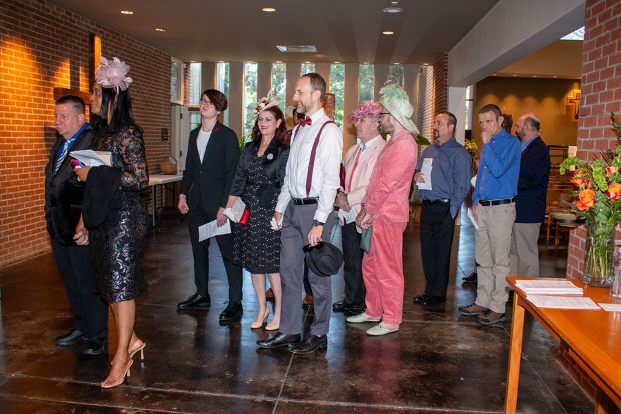 People standing in a lobby at a formal event, some in business attire holding programs.
