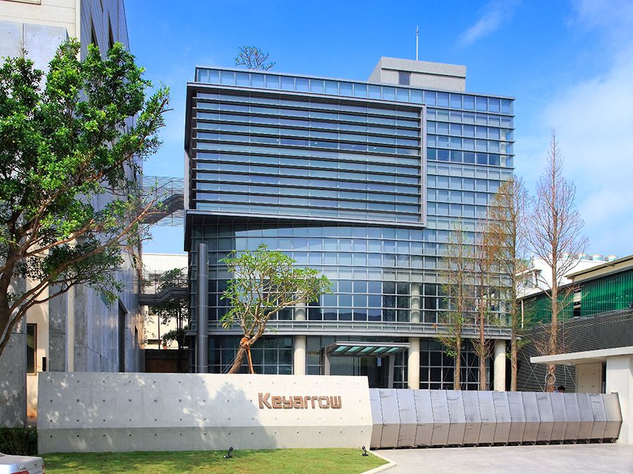 A large building with a lot of windows is surrounded by trees and grass.