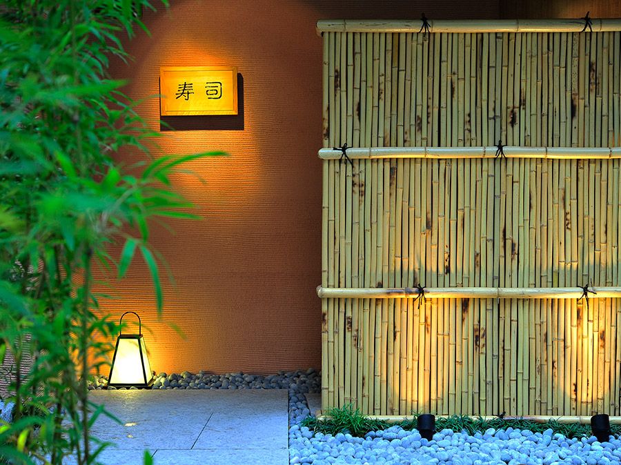 A bamboo fence surrounds a building with a sign on the wall.