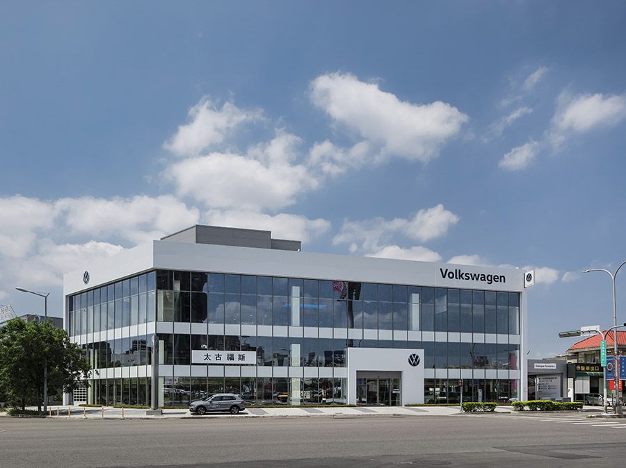 A volkswagen car dealership is located on the corner of a city street.