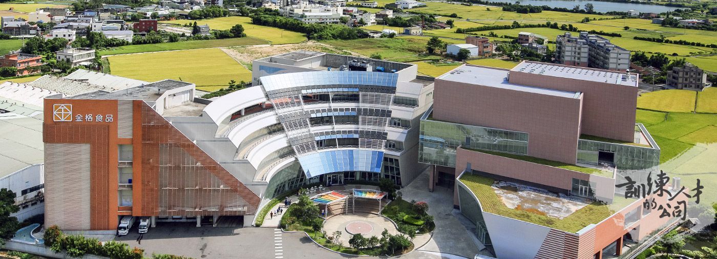 An aerial view of a large building with a green roof in the middle of a city.