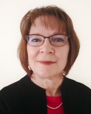 a woman wearing glasses and a black jacket is smiling for the camera .