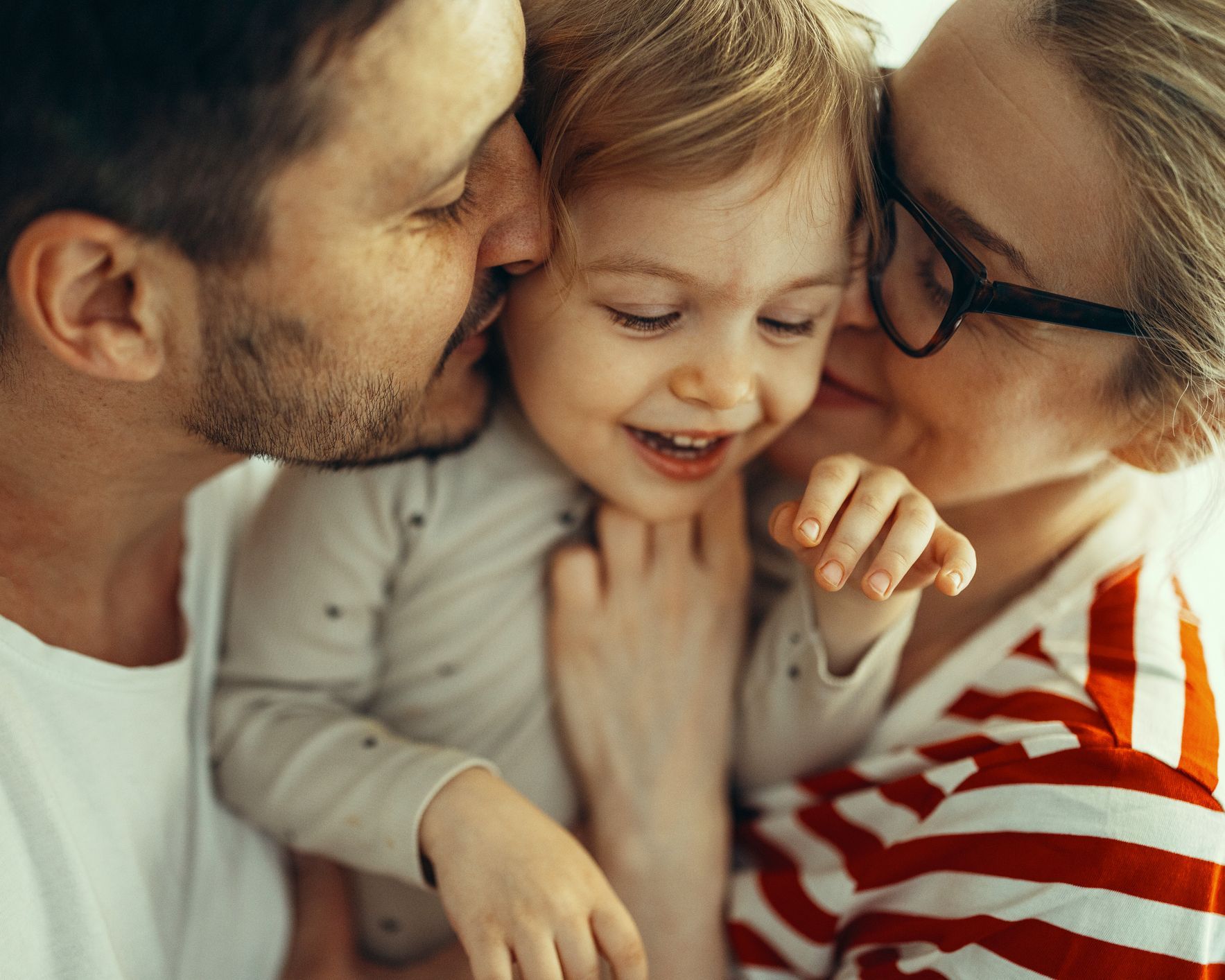 A man and woman lovingly kiss a child. A man and woman lovingly kiss a child.