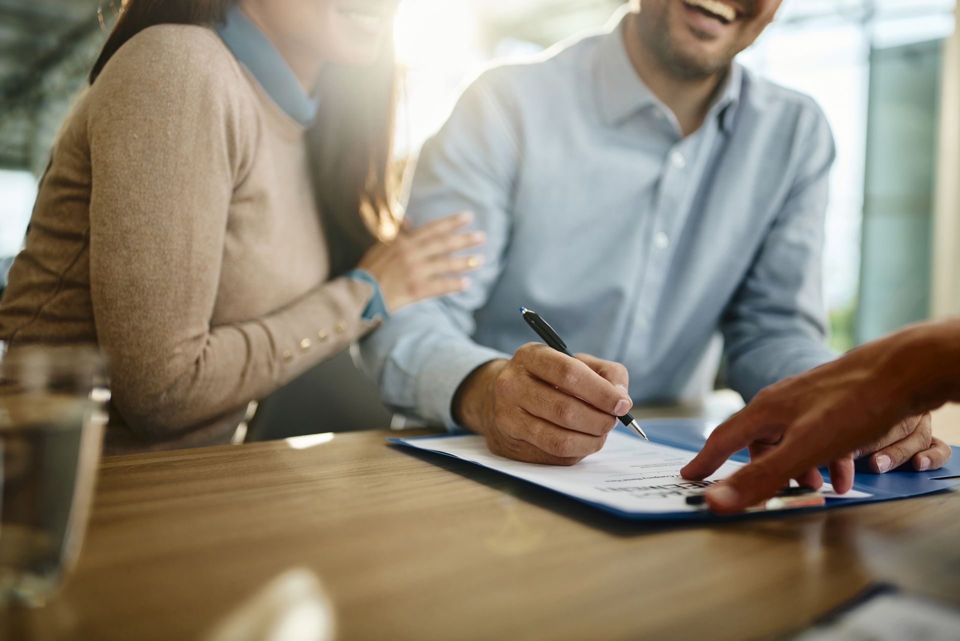 A man and a woman are sitting at a table signing a document. A man and a woman are sitting at a table signing a document.