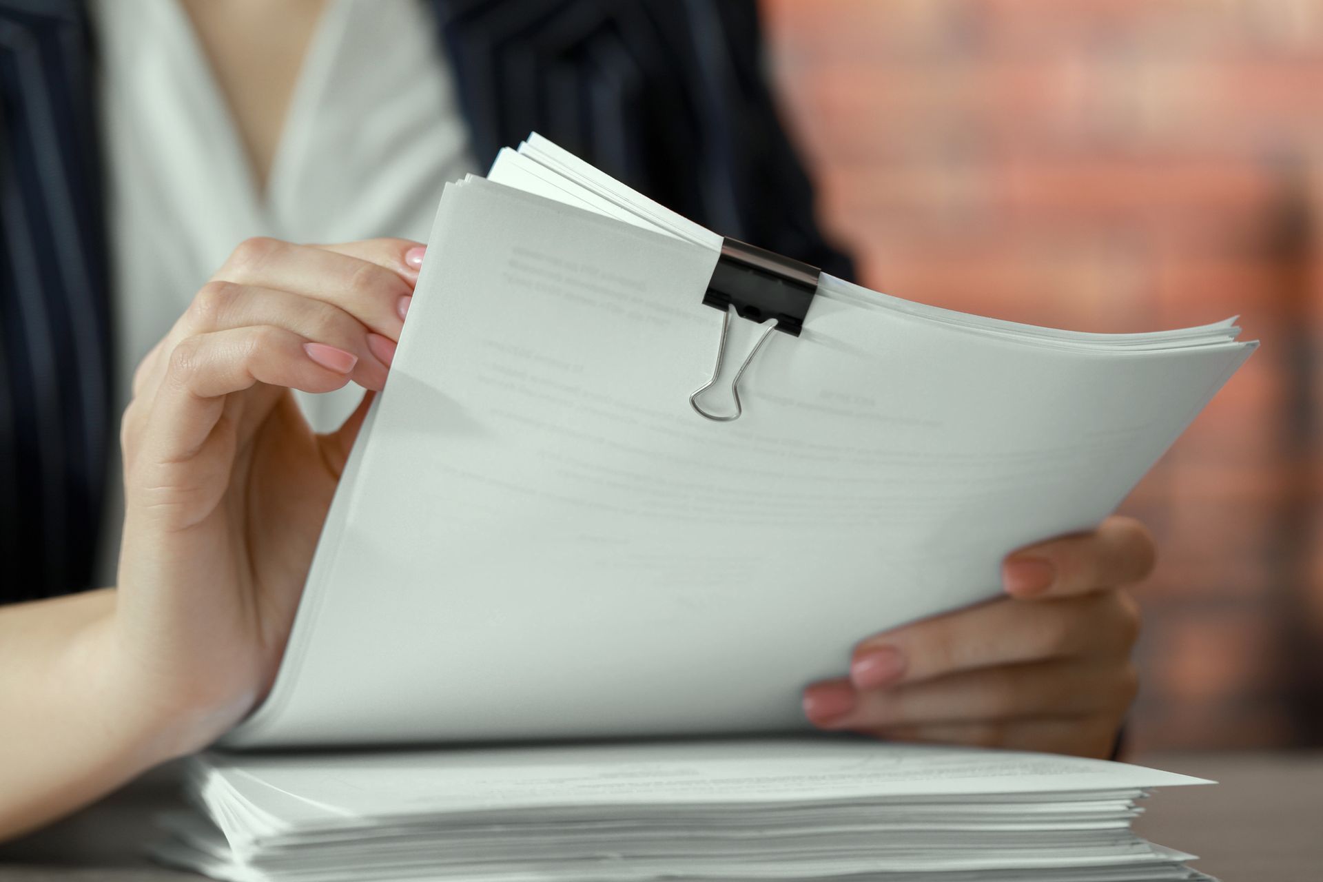 A woman is holding a piece of paper with a clip on it. A woman is holding a piece of paper with a clip on it.