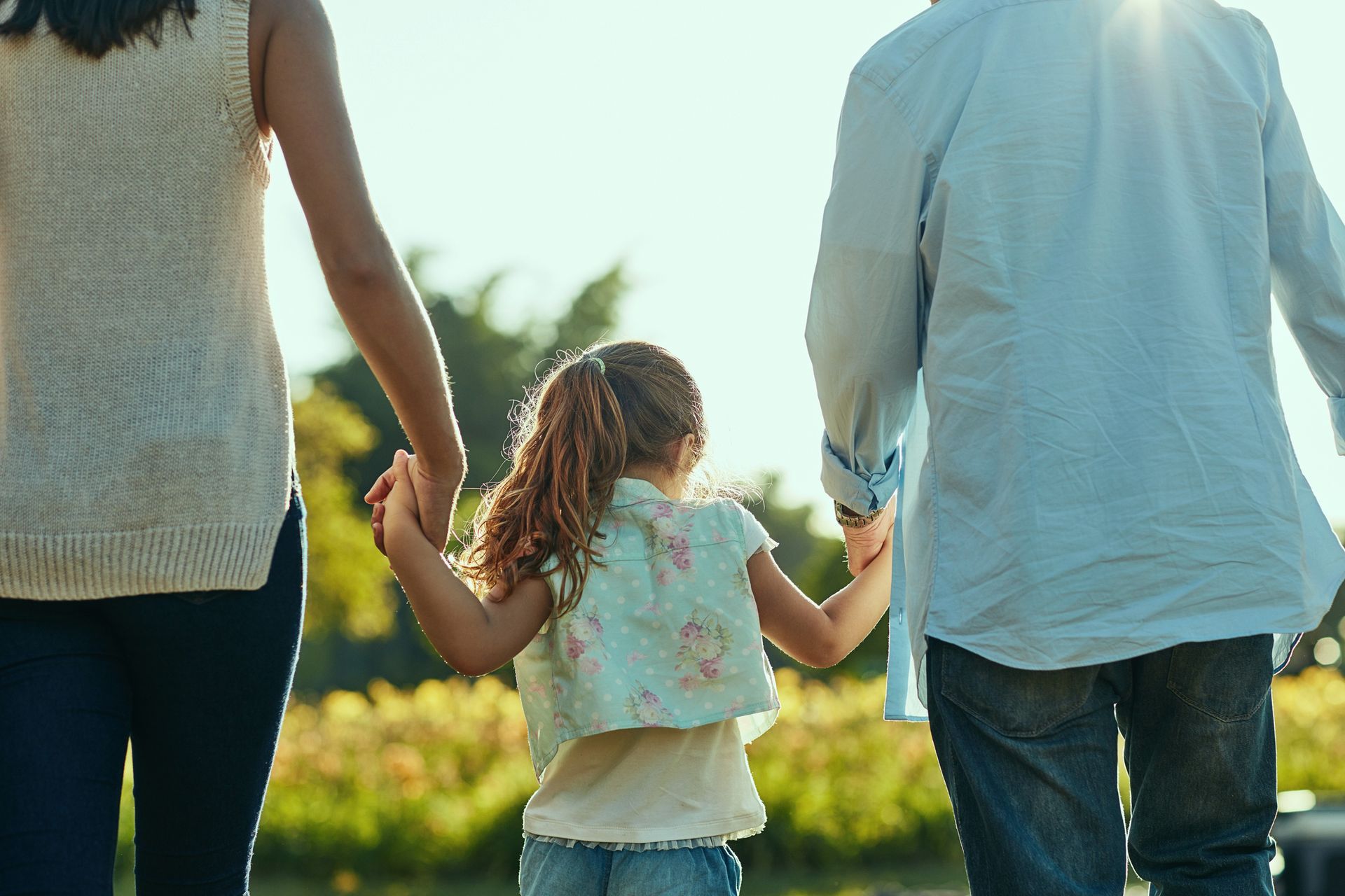 A family is holding hands while walking in a park. A family is holding hands while walking in a park.
