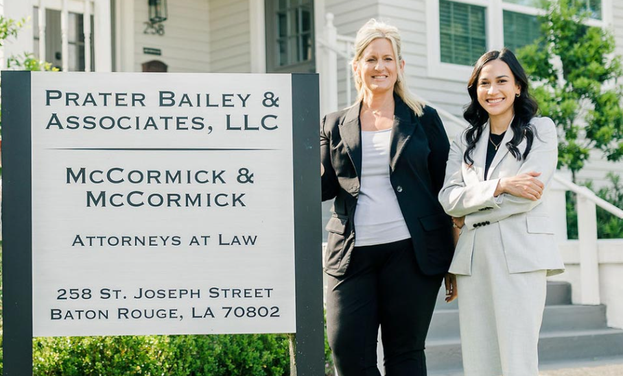 Two women standing in front of a prater bailey & associates llc sign Two women standing in front of a prater bailey & associates llc sign