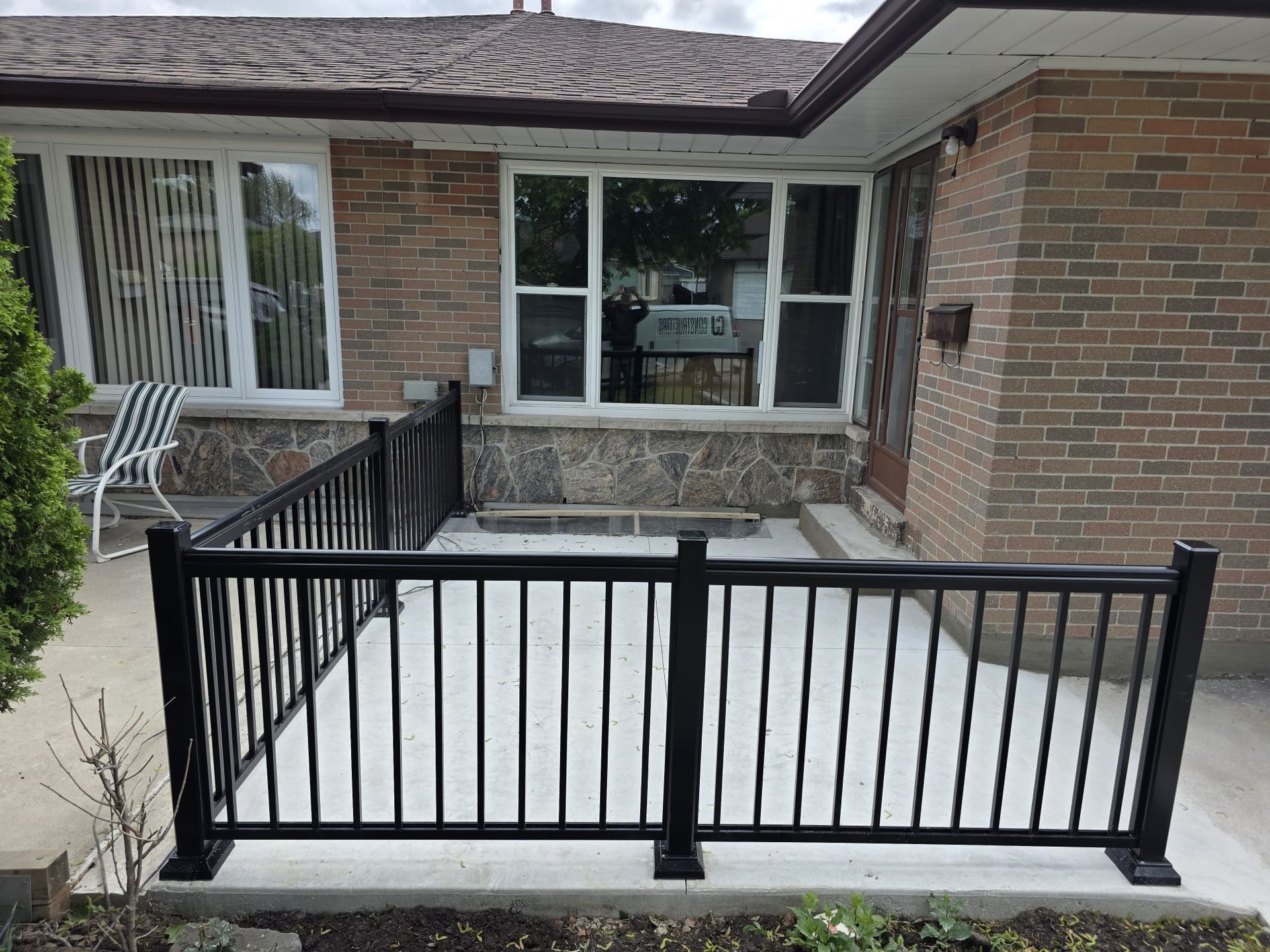 Front porch with black railing and wheelchair ramp leading to a brick house entrance