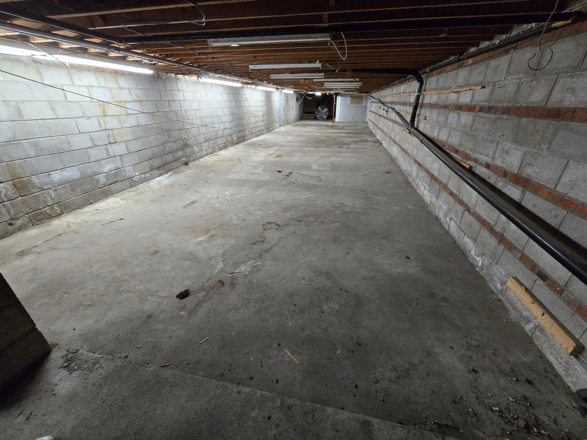 An empty basement with brick walls and a concrete floor