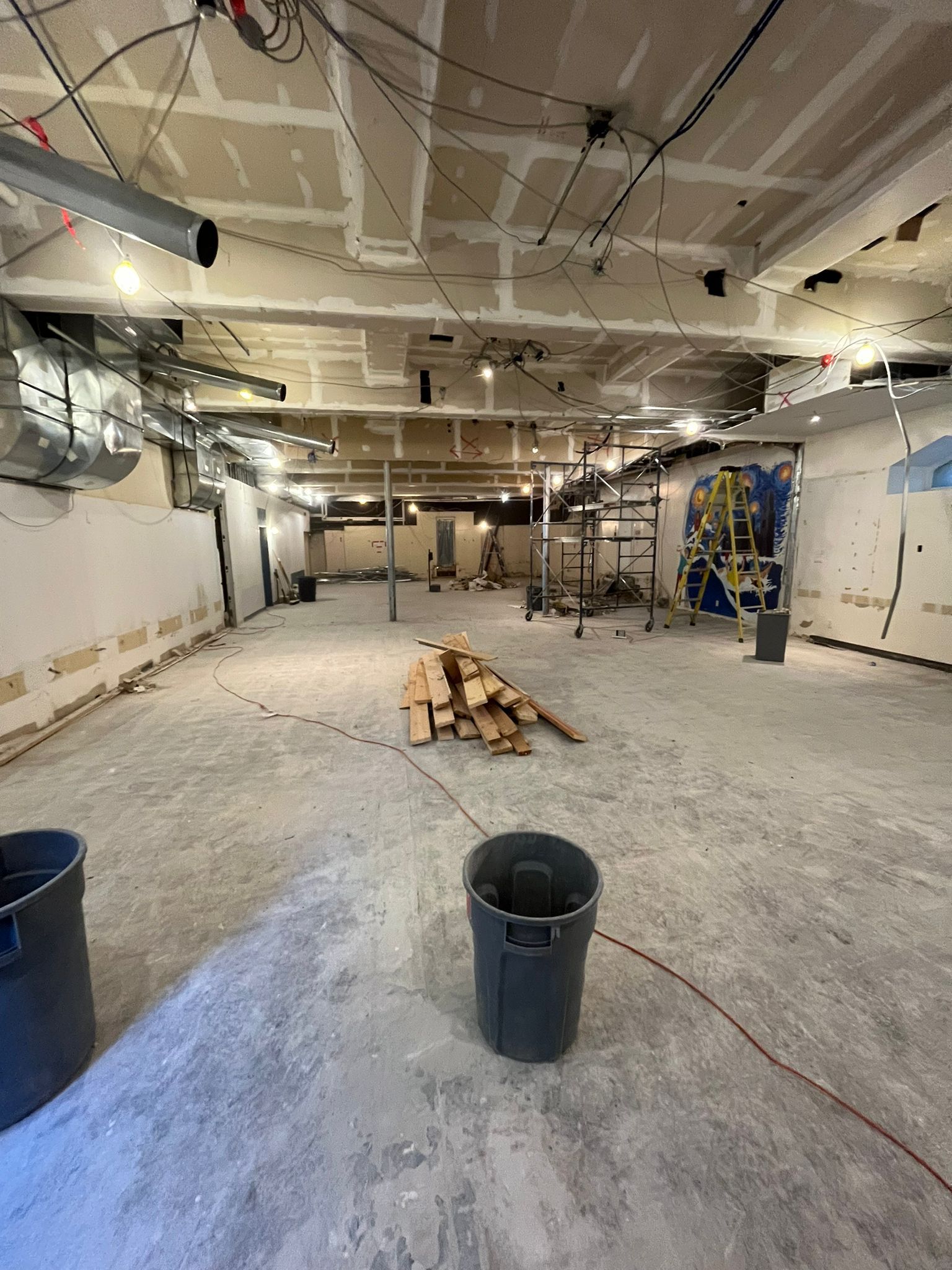 A large empty room with a trash can in the middle of it.