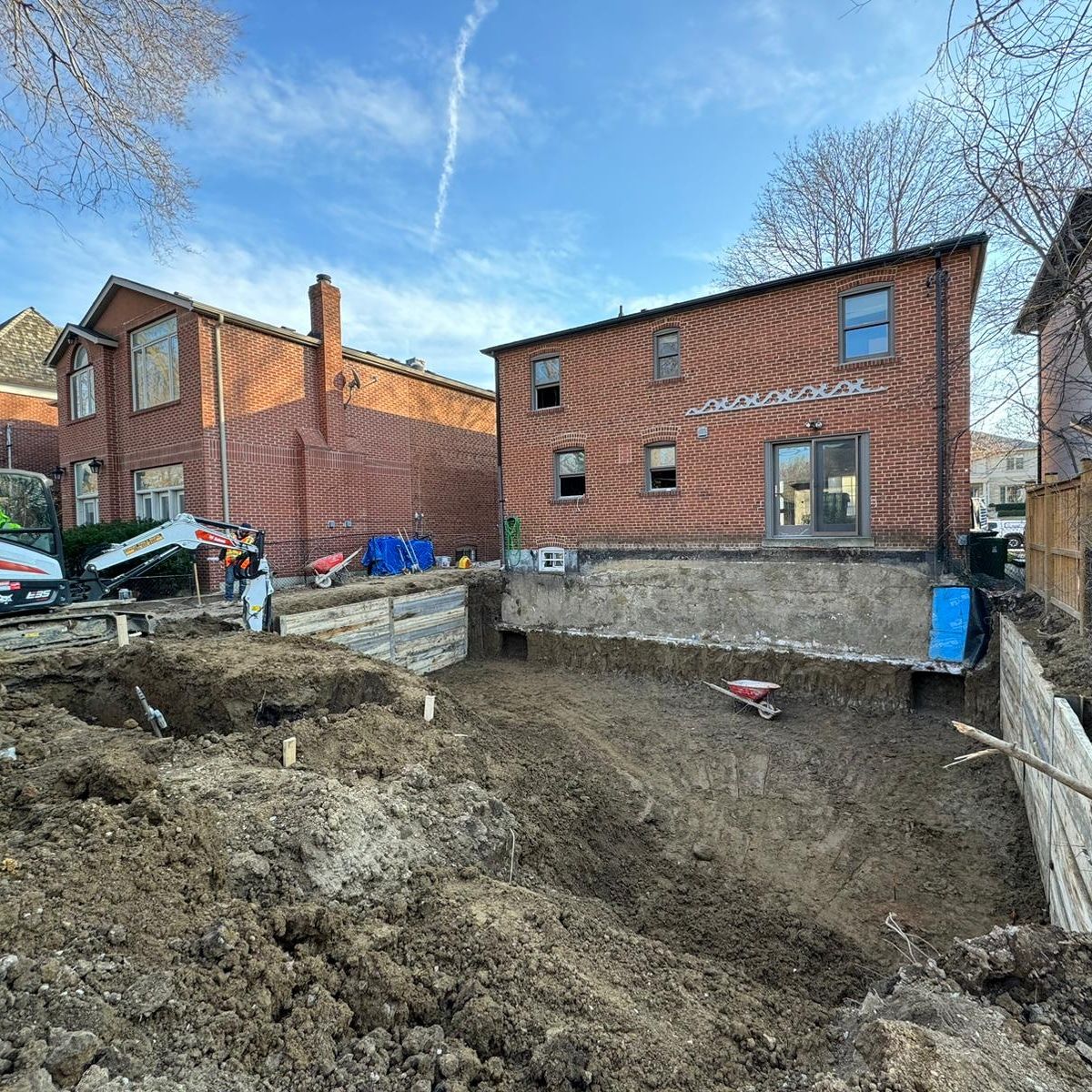 A large brick house is being built next to a large pile of dirt.