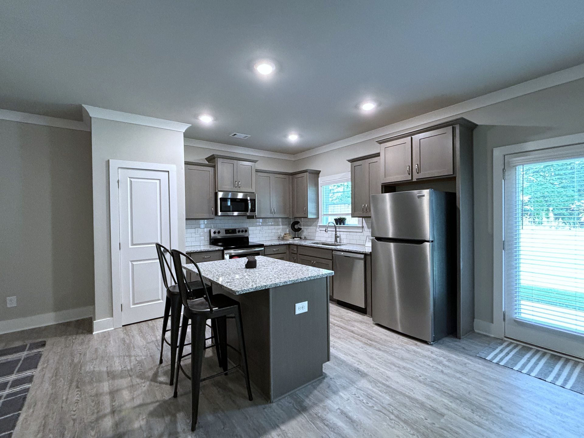 Modern kitchen with gray cabinets, stainless steel appliances, island, and sliding glass door to deck.
