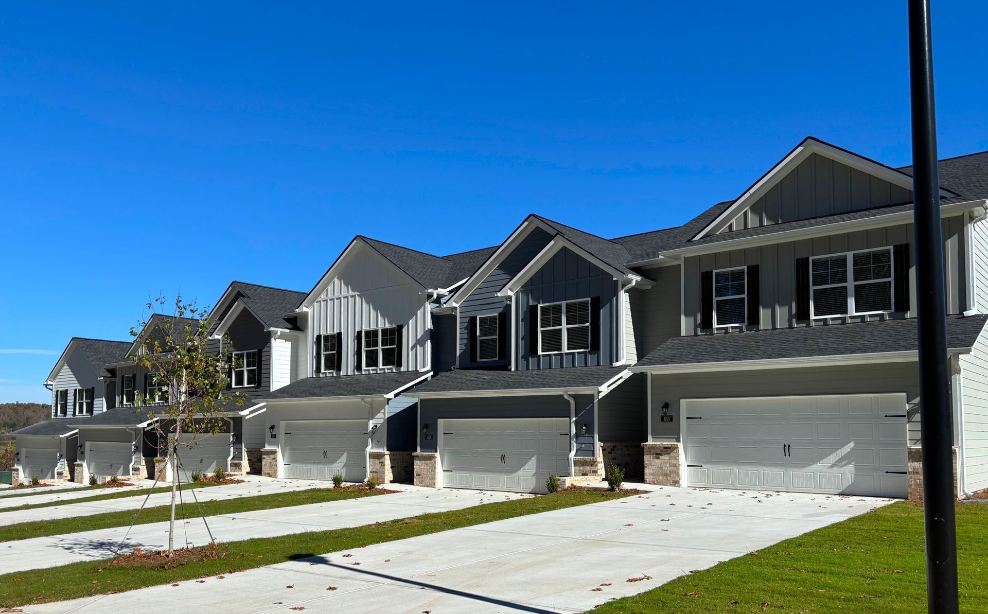 Row of newly built suburban townhouses with garages on a sunny day