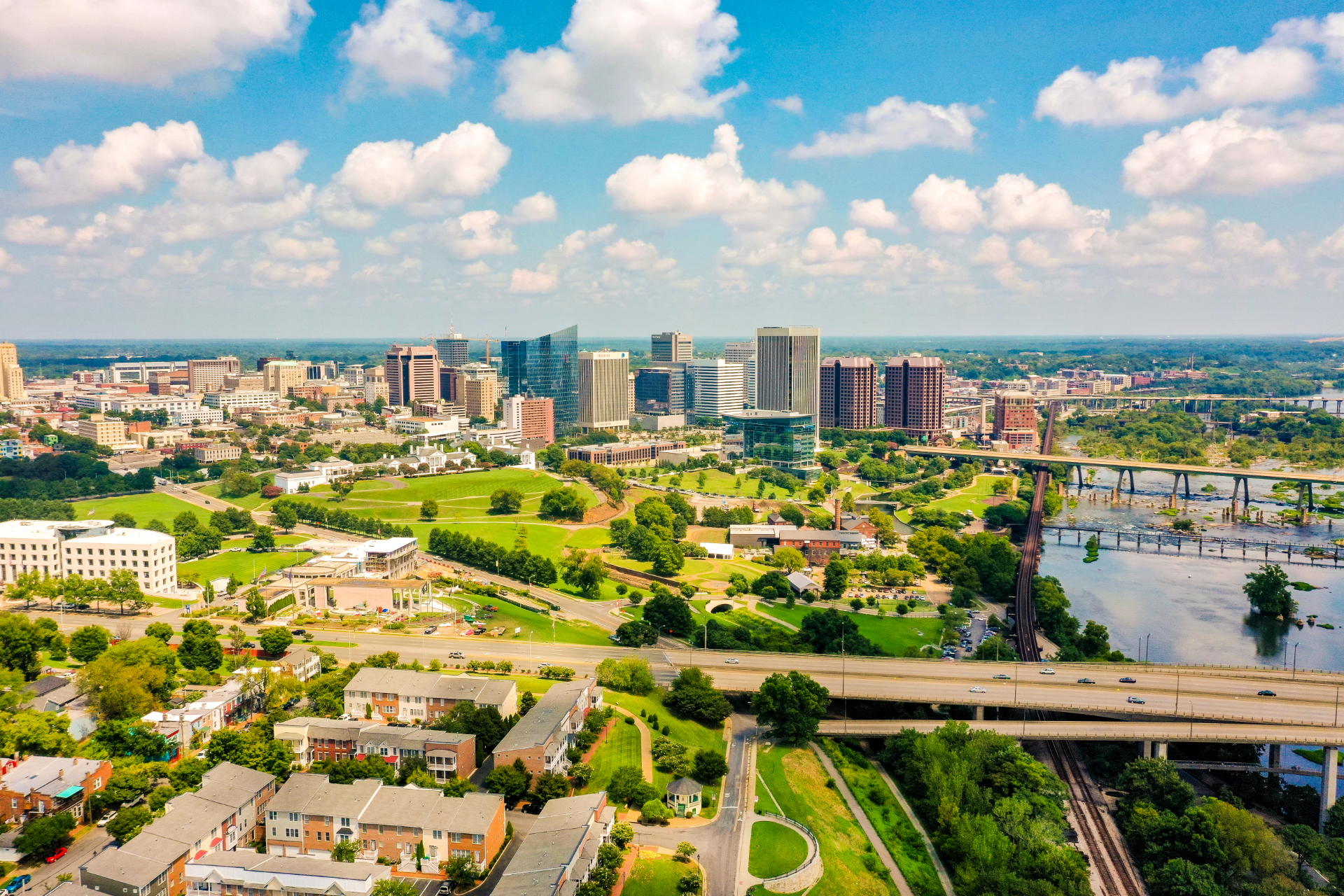 An aerial view of the Richmond, Virginia skyline, featuring the James River, bridges, and surrounding green parks.