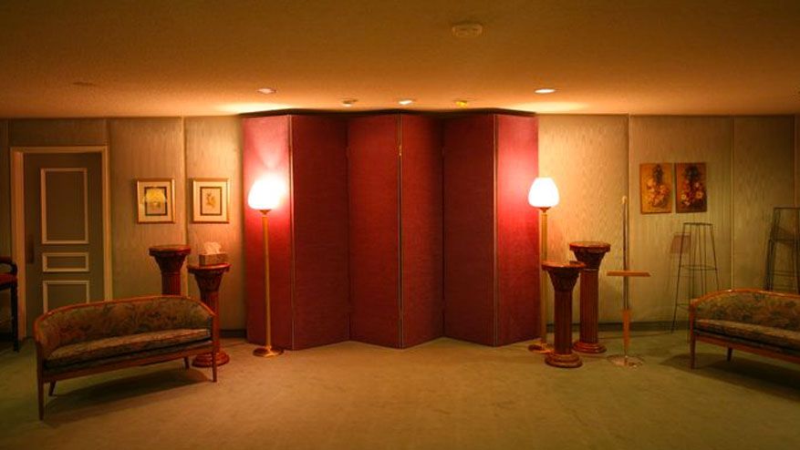 Elegant hotel room with red divider, wall lamps, small table, and upholstered benches on both sides