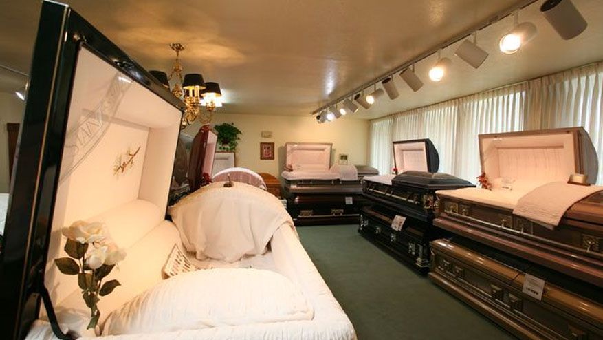 Funeral home viewing room with open caskets and white floral arrangements