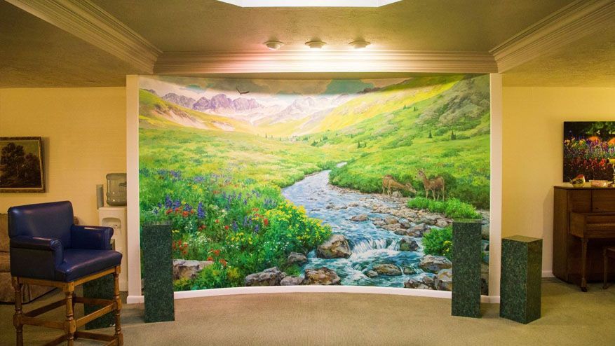 Bright mural of a winding stream and green hills in a warmly lit interior room