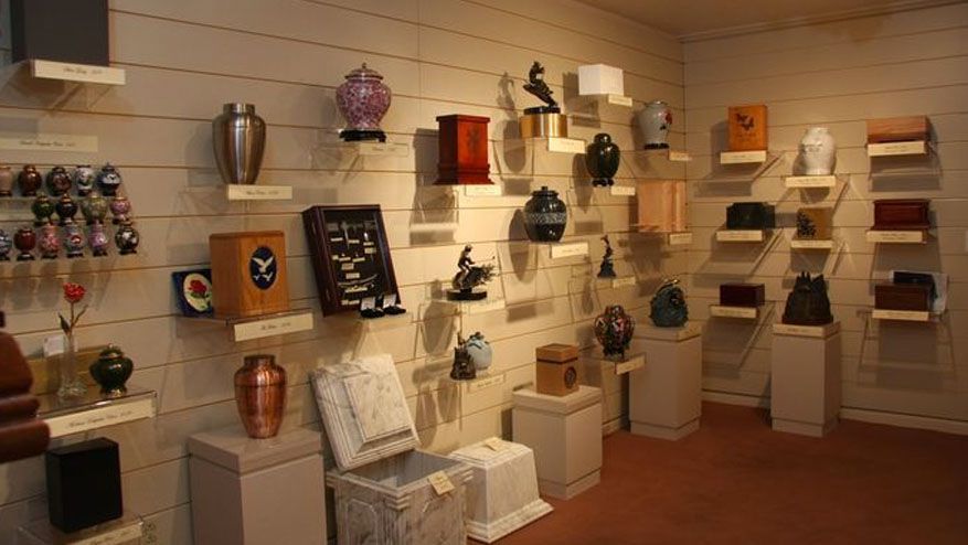 Memorial urns and keepsake boxes displayed on shelves in a gallery-like room