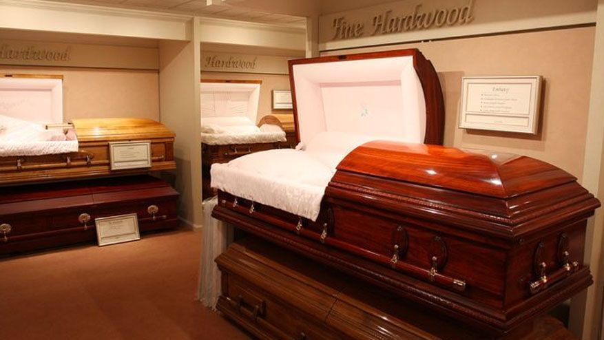 Showroom with open caskets in polished wood finishes and white interiors