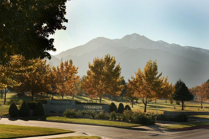 Mountain backdrop behind autumn trees and a park entrance sign in warm morning light