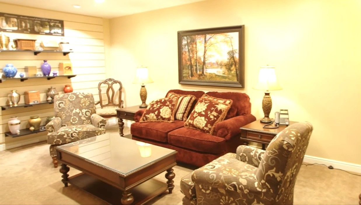 Cozy living room with red sofa, patterned chairs, wooden coffee table, and framed wall art